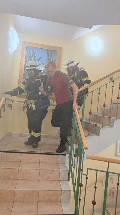 Zwei Feuerwehrleute gehen mit Mitarbeiter die Treppe hinunter
